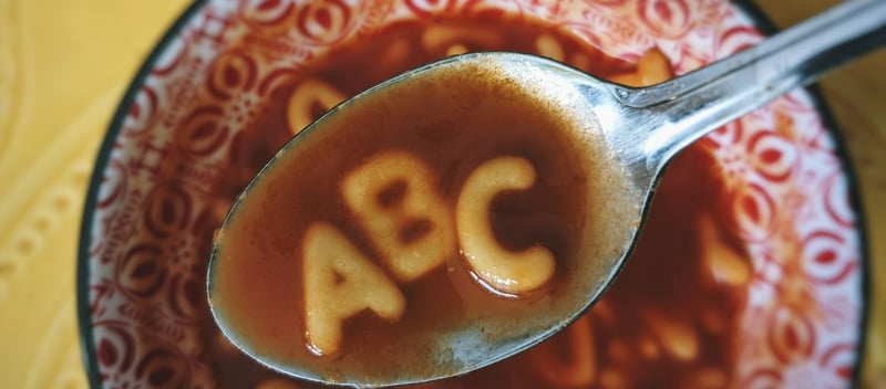 image of a bowl of alphabet soup with a spoon including letters A, B, and C