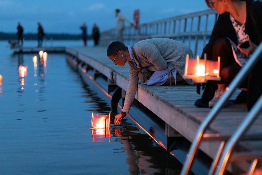 image of a woman placing a candle lantern on the water - image by oliver hotakainen - unsplash